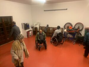 fotografia de várias pessoas numa sala a fazer um ensaio, duas delas estão em cadeira de rodas.